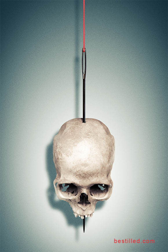 Skull impaled on a needle and hanging by a thread. Surreal art by Joseph Westrupp.