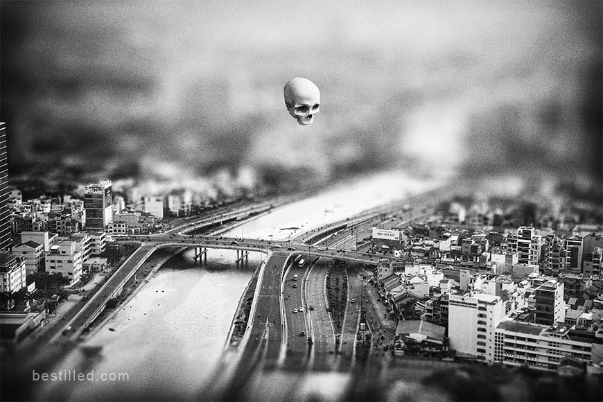 Skull floating over Ho Chi Minh City, Vietnam, surreal artwork in black and white by Joseph Westrupp.